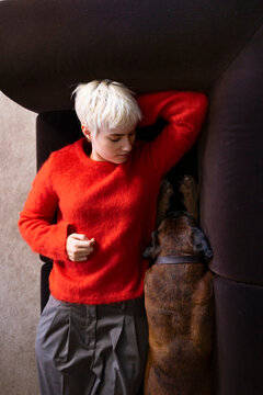 Young Woman in Red Sweater Lying on Couch With Dog 