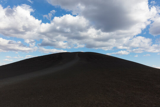 Mound of volcanic rock, clouds and sky above