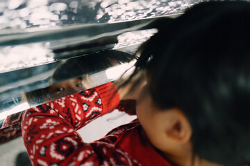 Child Exploring Reflections Under a Shiny Surface in a Playful Moment