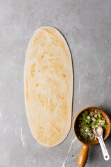 Overhead view of oil and flour mixture spread on raw chinese scallion pancakes dough, top view of homemade scallion pancakes, process of making cong you bing