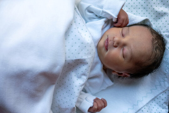 Closeup Of Newborn Baby Sleeping Wrapped In Hospital Blanket