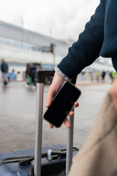 Man Waiting at Airport With Luggage and Boarding Pass on Phone