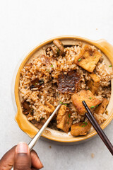 Overhead view of claypot rice with fried tofu and mushrooms in a spoon