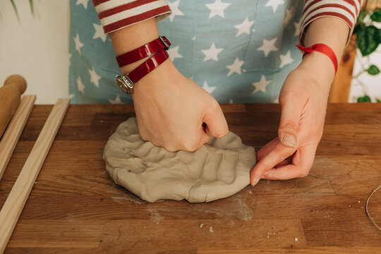 Pressing clay on wooden table during pottery work