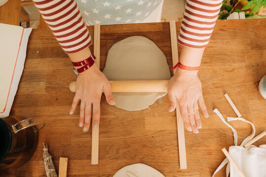 Rolling out clay slab with wooden rolling pin