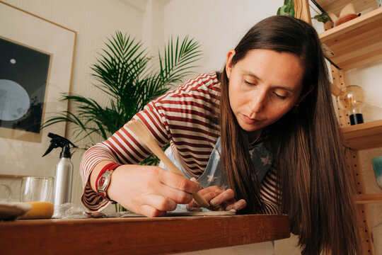 Woman carving clay piece with precision in cozy home pottery spa