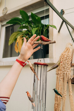Hand reaching for bird wind chime in garden patio space