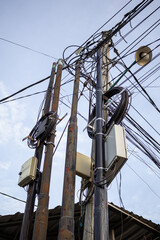 Overhead power lines creating a tangled mess against the sky, symbolizing urban challenges in infrastructure management and development with natural light