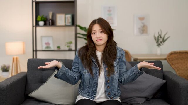 Confused Young Woman Shrugging on Living Room Sofa