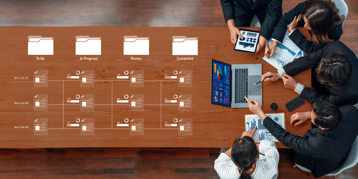 A diverse team collaborates around a table with digital tools and documents, enhancing workflow and communication in a modern office setting. Trope - Powered by Adobe