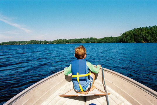 Boy rides on the bow of a motorboat on a lake in summer