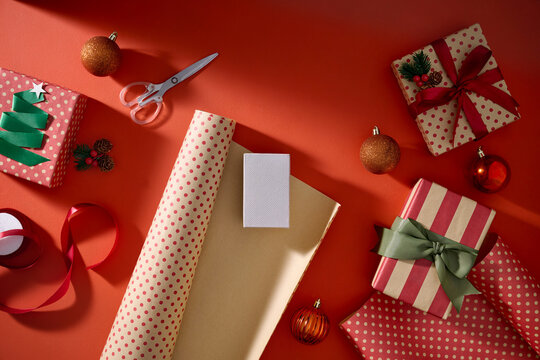 Christmas gifts and wrapping materials are arranged on a vibrant red