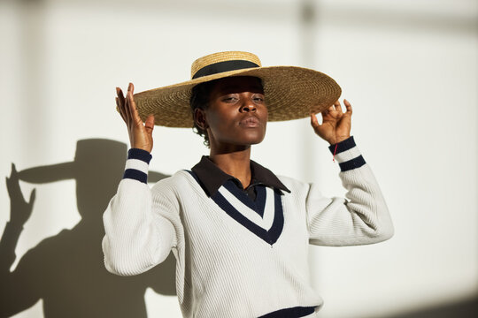 Model posing in a stylish straw hat against a bright background