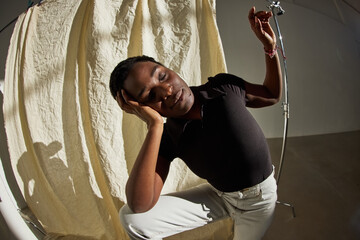 Young model poses gracefully in black outfit with neutral backdr