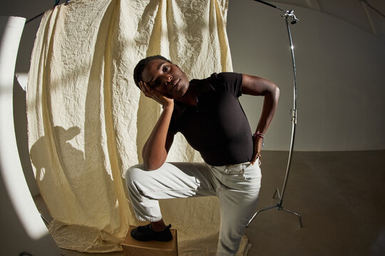 Model poses creatively in studio against textured backdrop