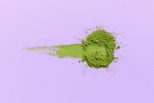 Vibrant green matcha powder artfully on a soft lilac background