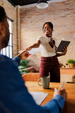 Woman colleague giving documents in office meeting