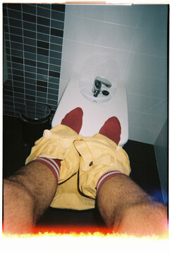 a man resting his feet on a bidet, 35mm film