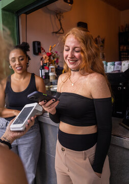 Young woman pays by contactless method at a bar