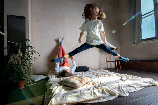 Child jumps on the bed while mom looks at the phone