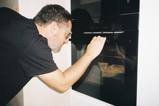 Man Watching Food in Oven
