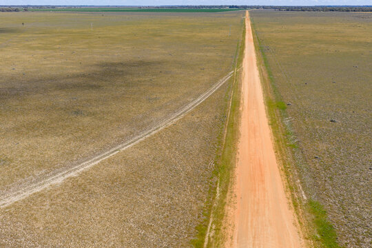 A long straight gravel road over dry farmland