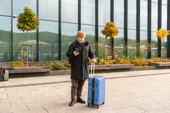 Man Waiting With Suitcase Outside Of Airport Building
