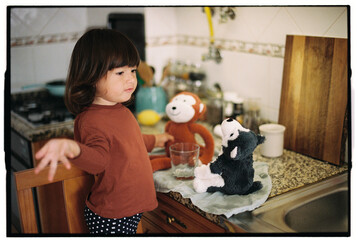 Child talking to stuffed animals in kitchen