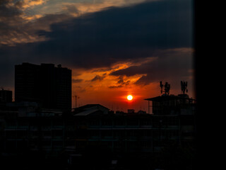 Dramatic sunset over city buildings silhouette, urban evening landscape and orange sky concept.