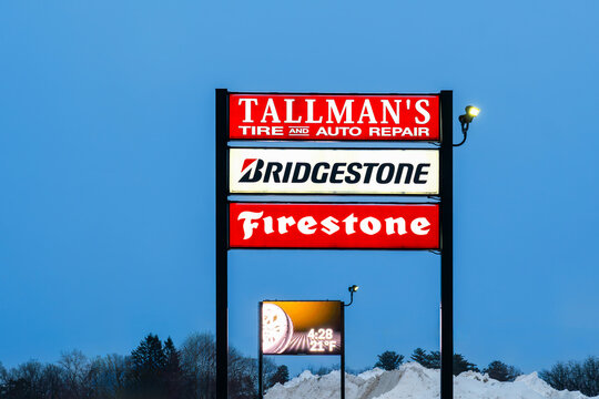 Yorkville, NY - Jan 5, 2026: Tallman&rsquo;s Tire and Auto Repair roadside sign with Bridgestone and Firestone branding, lit pylon sign against night sky, and snow-covered surroundings in winter