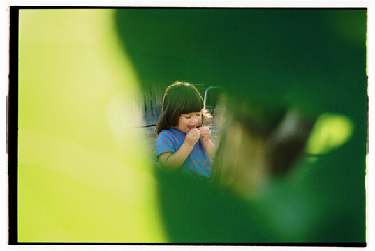 Laughing child through bright green leaves