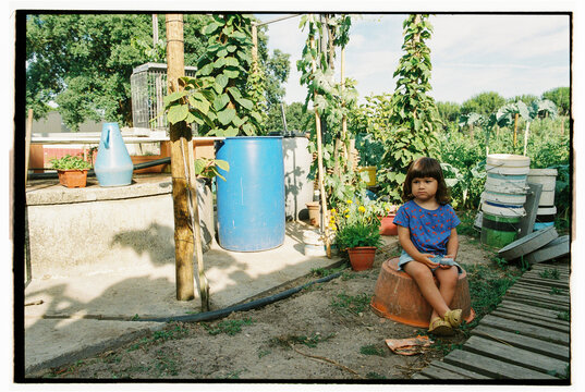 Child sitting in garden with blue barrel