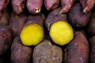 Close-up of roasted Japanese sweet potatoes, showing vibrant yellow flesh inside purple skin. Delicious, healthy street food snack with sweet and soft texture.