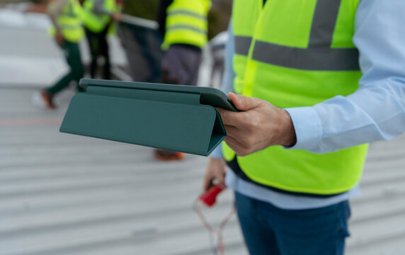 Construction supervisor holding tablet inspecting industrial rooftop w