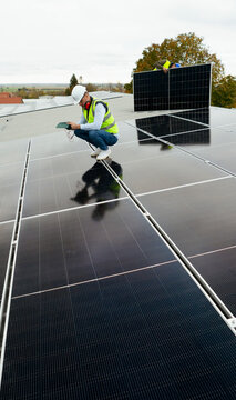 Technician checking solar panel system during rooftop inspection
