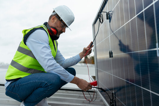 Engineer checking solar panel performance with multimeter
