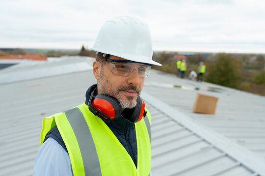 Mature worker wearing safety gear on factory rooftop
