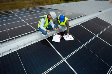 Solar panel engineers checking plans on a rooftop
