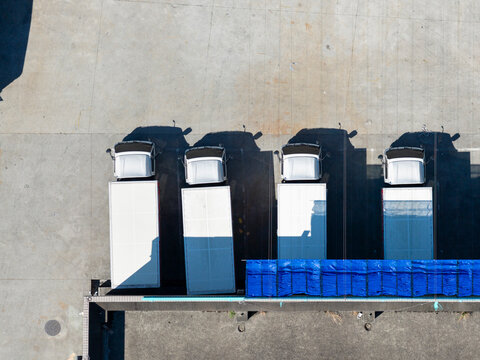 Four semitrailer trucks at a logistics loading dock