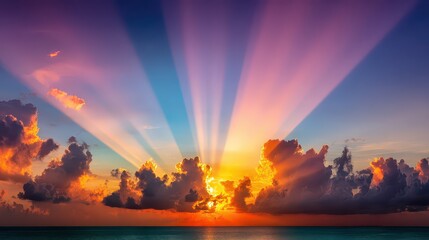 Dramatic Sunset Over Ocean with Golden Sun Rays Shining Through Colorful Clouds in a Wide Sky Reflecting on Calm Water Landscape