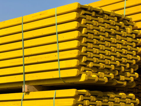 Stack of bundled bright yellow wooden construction beams
