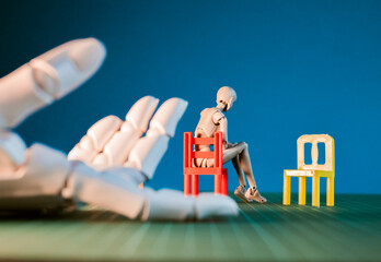 Hand reaching toward mannequin sitting in chair
