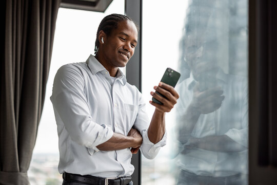 Happy American Man in Business Casual, Using Smartphone by Window 
