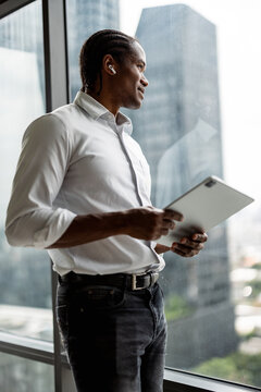 Professional Man With Tablet By Window Enjoying Busy Urban View
