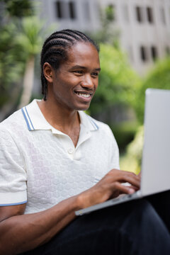 Happy Man With Cornrows Working On Laptop Outdoors 