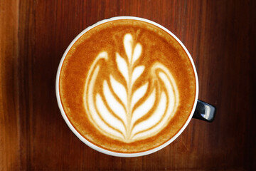 a cup of latte art coffee on wooden background