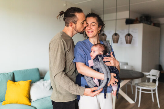 Parents Affectionately Looking at Baby in Carrier at Home