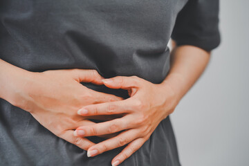 Close-up of woman pressing lower abdomen with both hands, showing pain or cramps, suitable for medical, health, or wellness content.