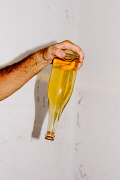Unknown hand angling a wine bottle downward to release settled residue