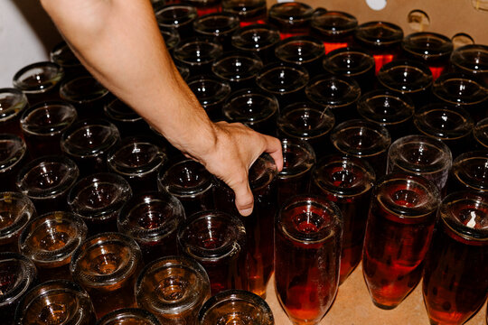 Anonymous hand arranging a batch of newly produced wine bottles